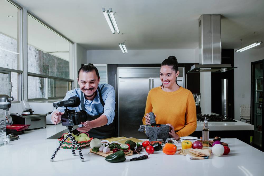 Two people cooking and filming the process in a kitchen