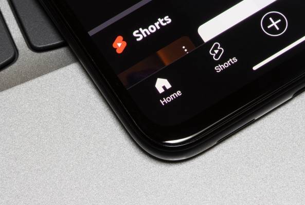 Close-up of smartphone showing YouTube Shorts and Home icons on app interface.
