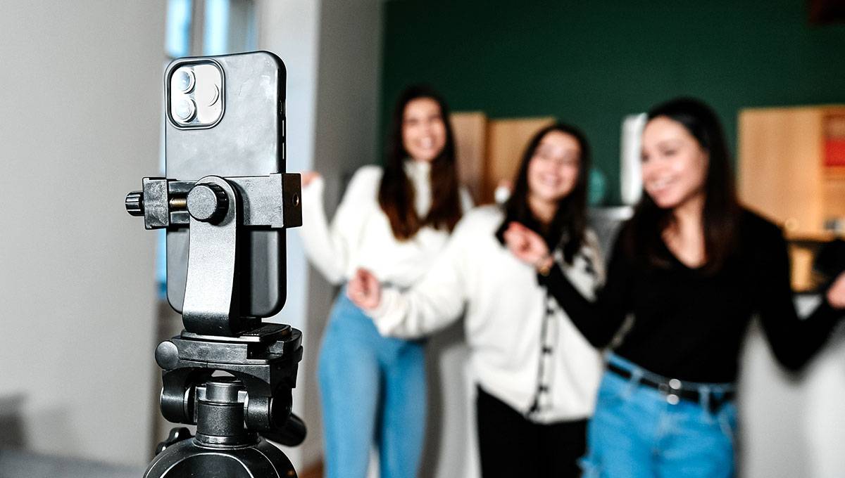 Three women filming a trendy youtube short on a smartphone