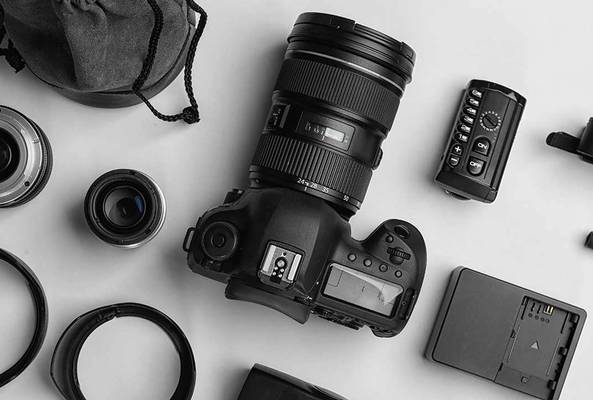 DSLR camera with lens and photography accessories on a flat surface in black and white.