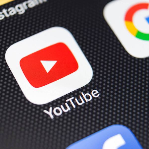 Close-up of YouTube app icon on smartphone screen with other social media icons visible