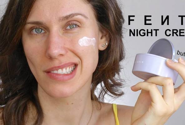 Woman with cream on cheek holding Fenty Night Cream container questioning its use
