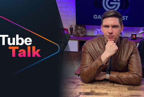 Man in brown leather jacket hosting Tube Talk podcast with gaming-themed background