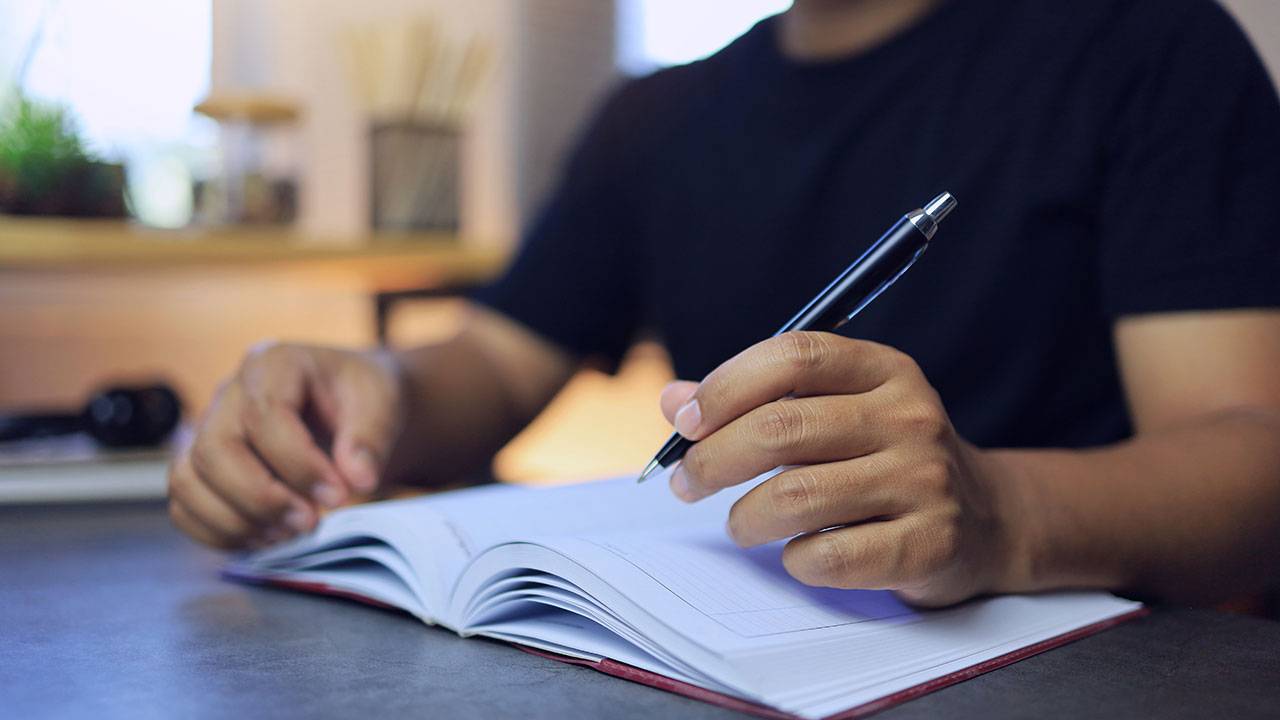 man writing his goals in a journal