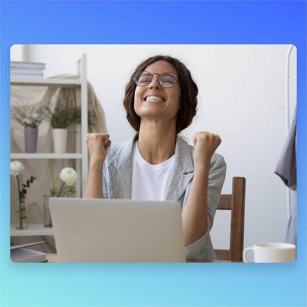Happy woman celebrating success while working on laptop at home office desk