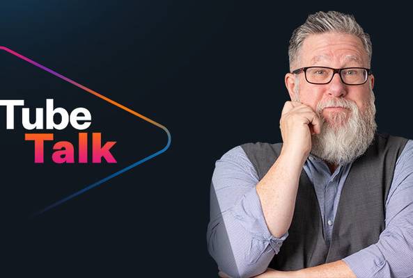 Middle-aged man with beard and glasses beside colorful Tube Talk logo on black background