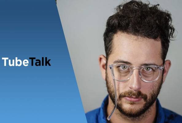 Man with curly hair and glasses next to blue gradient background with "TubeTalk" text