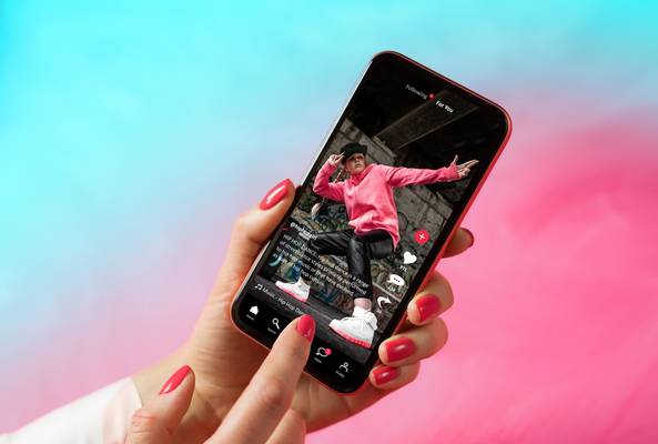 Hand holding smartphone showing hip hop dance video on social media app screen.
