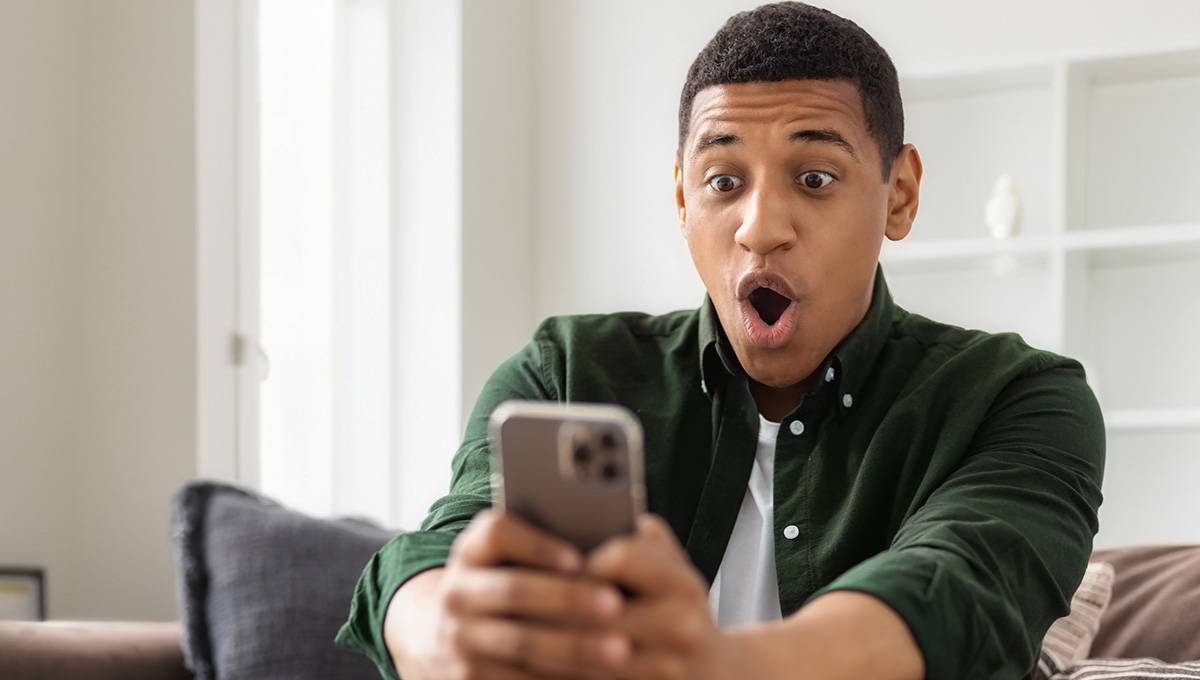 An excited man looking at his phone in shock