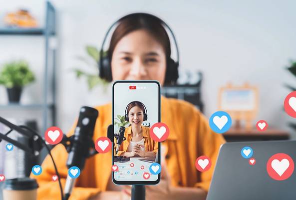 Woman live streaming with microphone, headphones, and social media heart icons.