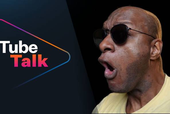 Man wearing sunglasses speaking beside "Tube Talk" logo on black background.