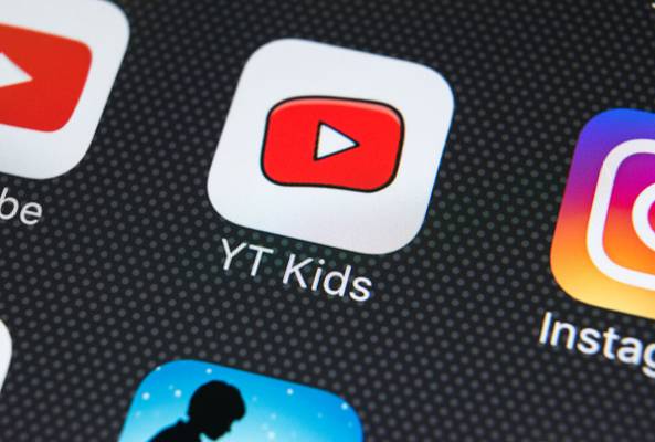 Close-up of YT Kids app icon on smartphone screen with other social media apps visible