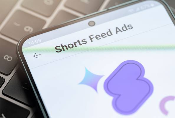 Smartphone screen displaying Shorts Feed Ads page on keyboard background for marketing.