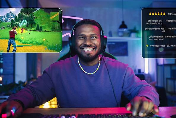 Smiling gamer playing online video game with headphones and live chat on screen at night