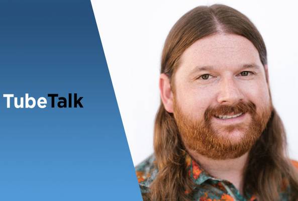 Smiling man with long hair and beard beside TubeTalk logo on blue gradient background