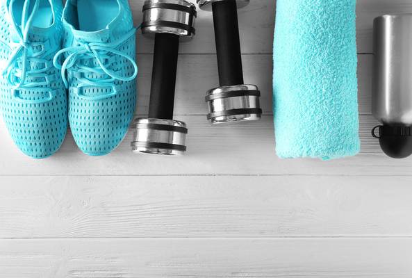 Blue running shoes, dumbbells, towel, and water bottle on white wooden floor
