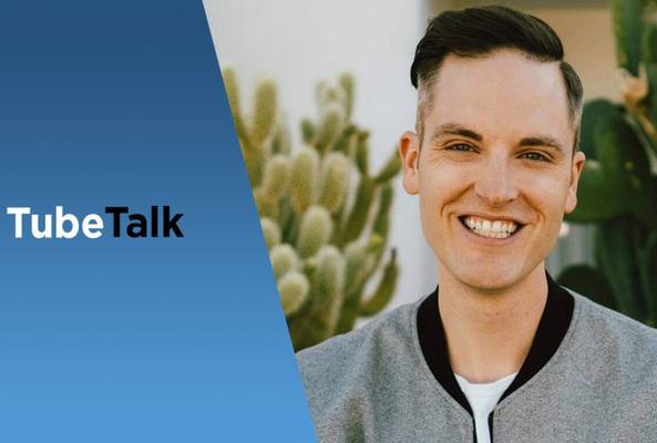 Smiling man in jacket next to blue background with TubeTalk logo and cactus plants