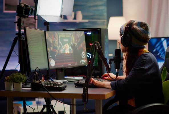 Female gamer streaming gameplay on dual monitors with professional microphone and headset