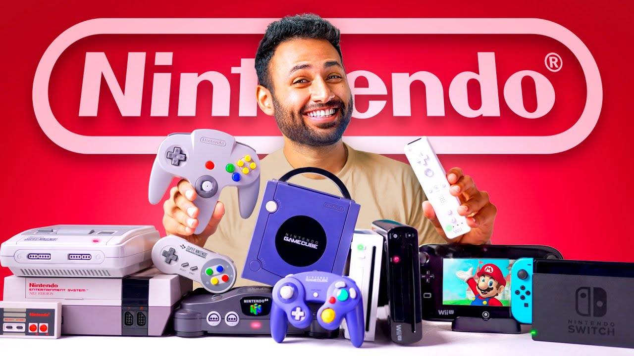 A man smiling beside a pile of gaming consoles