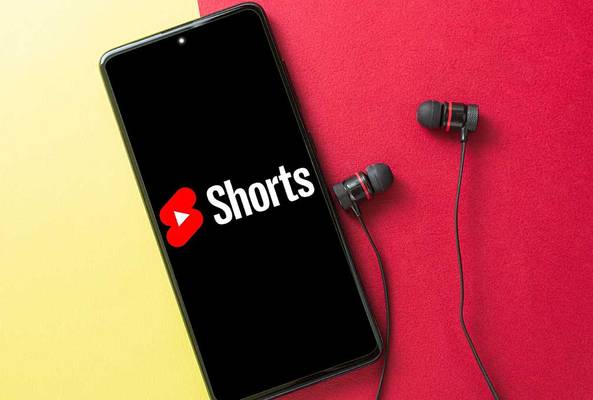 Smartphone displaying YouTube Shorts logo with black and red earphones on red background
