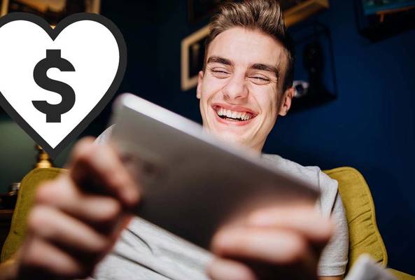 Young man smiling using tablet with dollar sign heart icon symbolizing online earnings