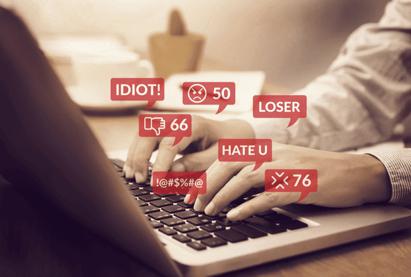Person typing on laptop with digital hate speech and negative comments overlay.