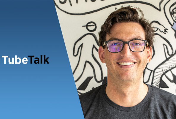 Smiling man wearing glasses with TubeTalk logo and illustrated background behind him