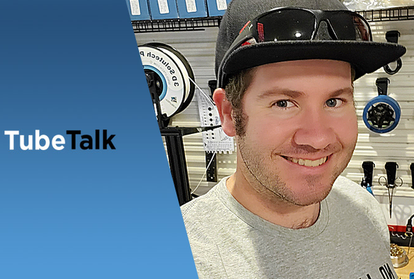 Smiling man in cap and sunglasses with fishing gear and TubeTalk logo on blue background