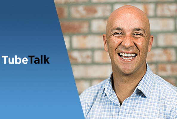 Smiling bald man in checkered shirt beside blue panel with TubeTalk logo text