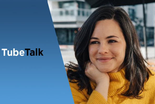 Young woman in yellow sweater smiling, TubeTalk logo on blue background beside her
